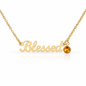Gold script affirmation necklace reading 'Blessed' with a small round amber gemstone accent, shown on a white background with a soft reflection.