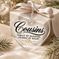 A heart-shaped clear acrylic Christmas ornament with black script reading 'Cousins' and the phrase 'Family by Blessing. Friends by Heart.