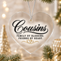 A heart-shaped clear acrylic Christmas ornament with black script text reading 'Cousins' and the phrase 'Family by blessing. Friends by heart.