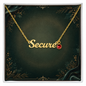 A gold nameplate affirmation necklace spelling 'Secure' with a small red gemstone accent, presented on a dark green decorative display card.