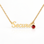 Gold affirmation necklace spelling 'Secure' with a small round red crystal charm, shown on a white background with a soft reflection.