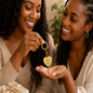 Two women holding a sisters engraved keychain with heart-shaped tags, smiling and looking at each other.